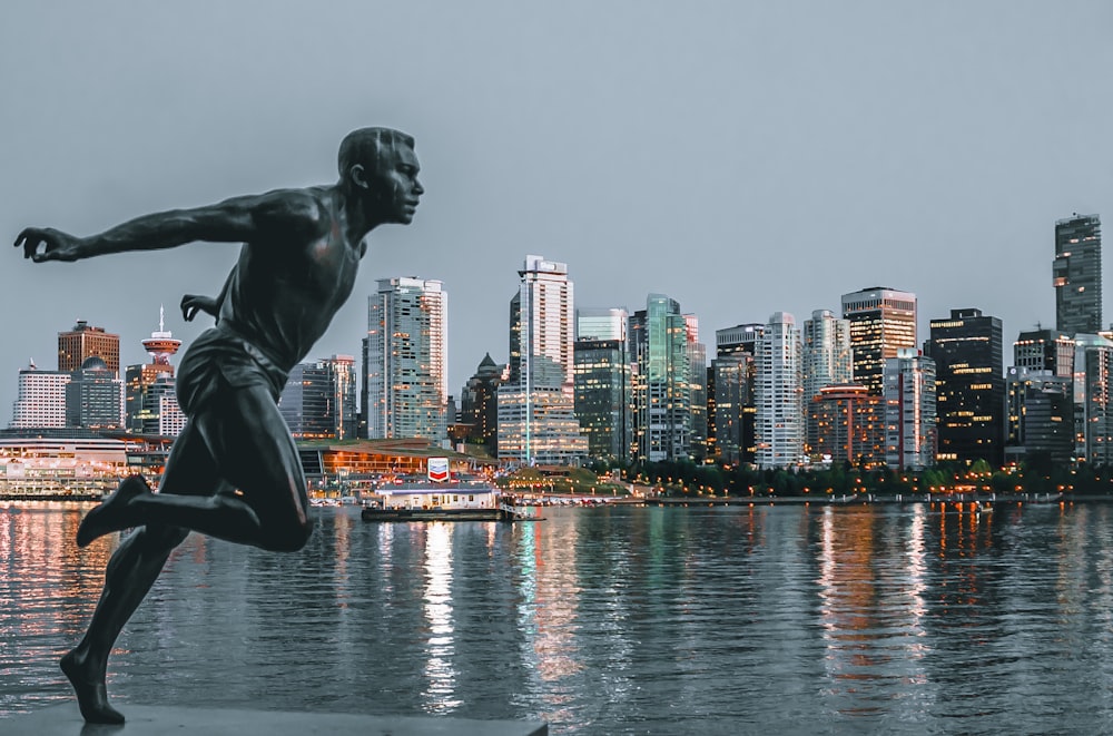 statue of topless man on concrete platform near body of water during daytime