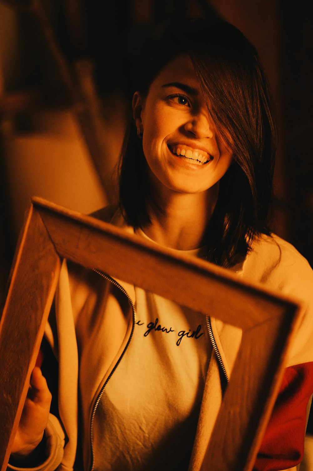 smiling woman holding brown wooden frame