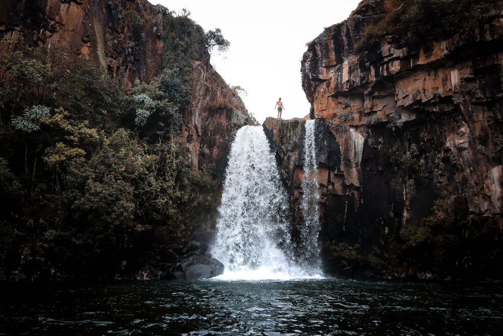 uomo in piedi sulla cima delle cascate