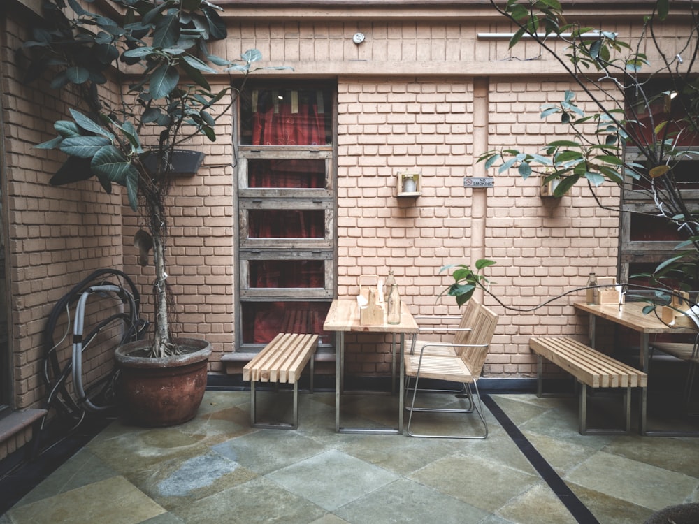 table and chair beside brick wall and green-leafed plant