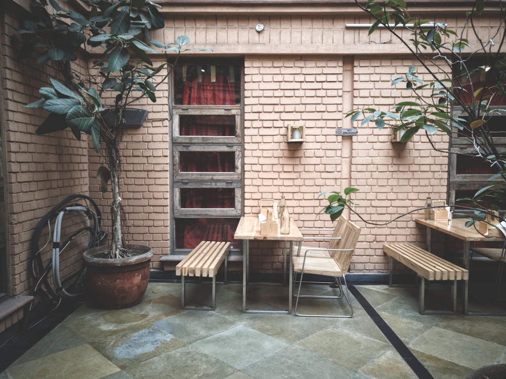 Tisch und Stuhl neben Backsteinmauer und grünblättriger Pflanze