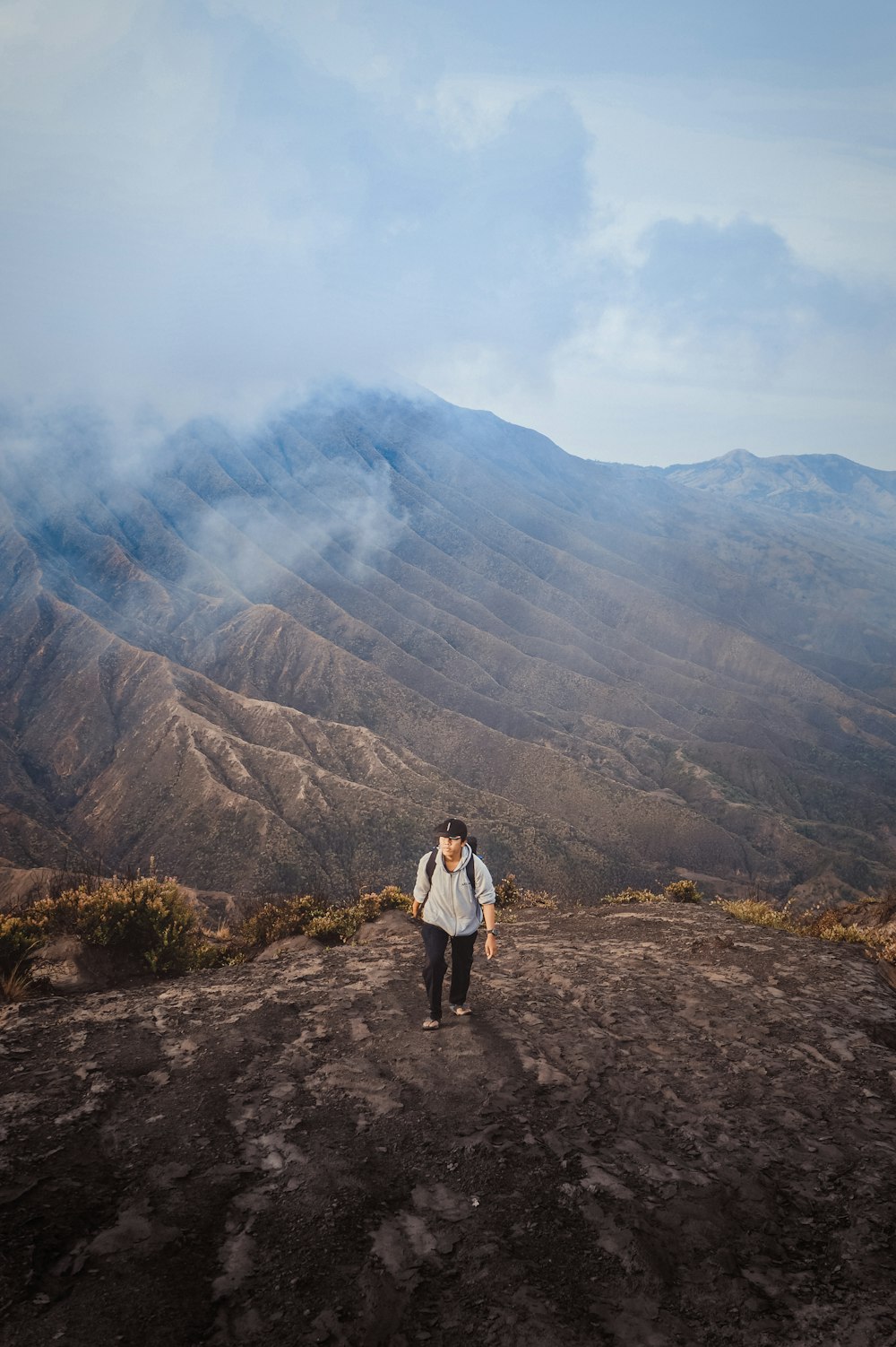 aerial view photography of man standing on cliff during daytime