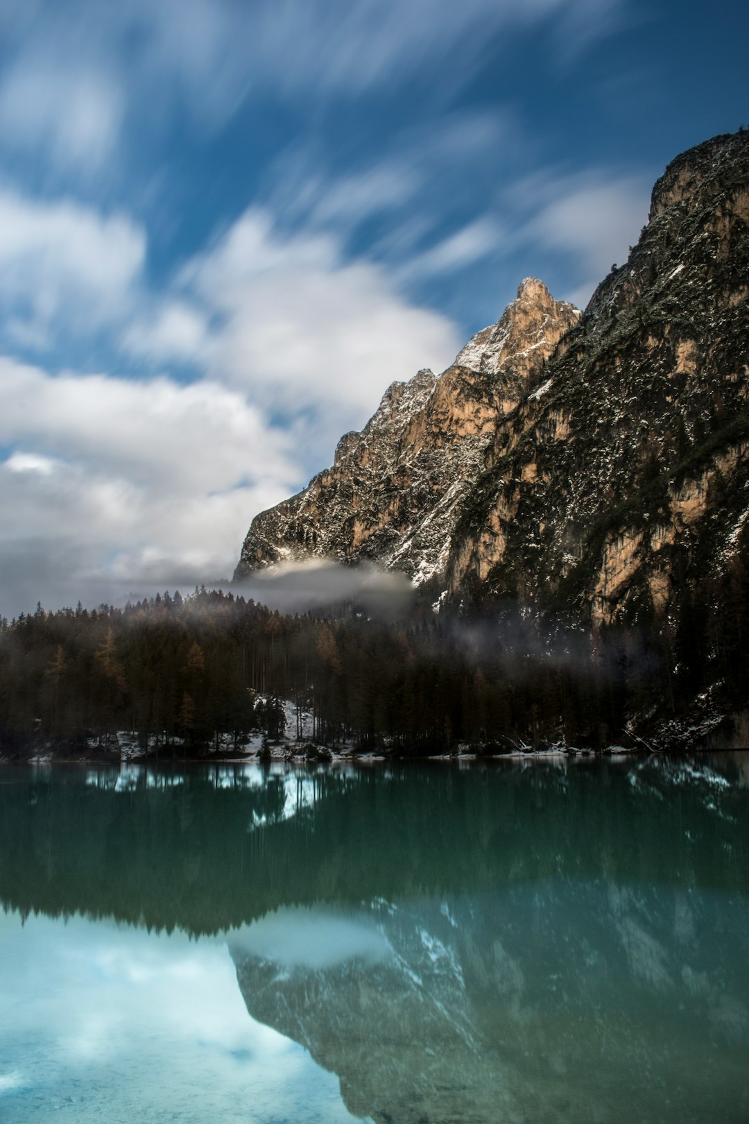 mountains by the body of water under cloudy sky