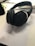 On a desk lies a pair of black over-ear headphones resting on a paper with mathematical text. Nearby, there are open books, part of a smartphone, and writing instruments, suggesting a study or work environment.
