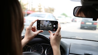 A person scanning a billboard with a smartphone while driving.