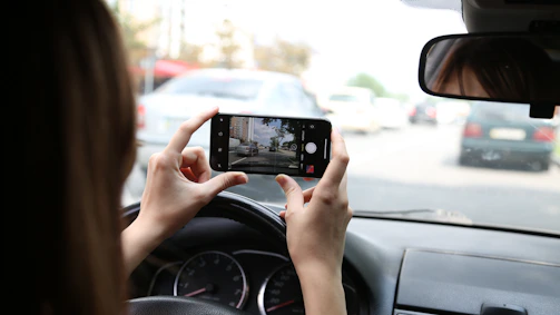 A friendly roadside scene with a driver using a smartphone to report a hazard.