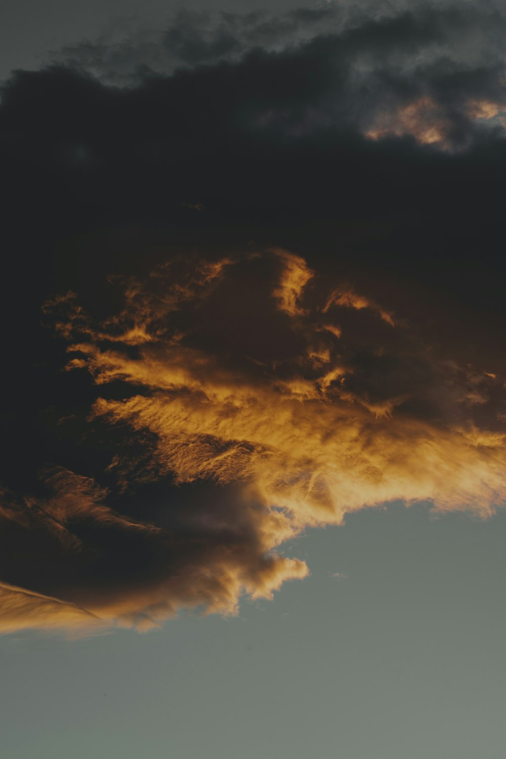 a plane flying through a cloudy sky at sunset