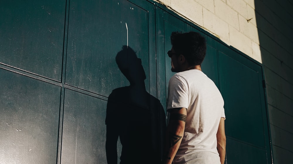 homme en t-shirt blanc debout devant le mur