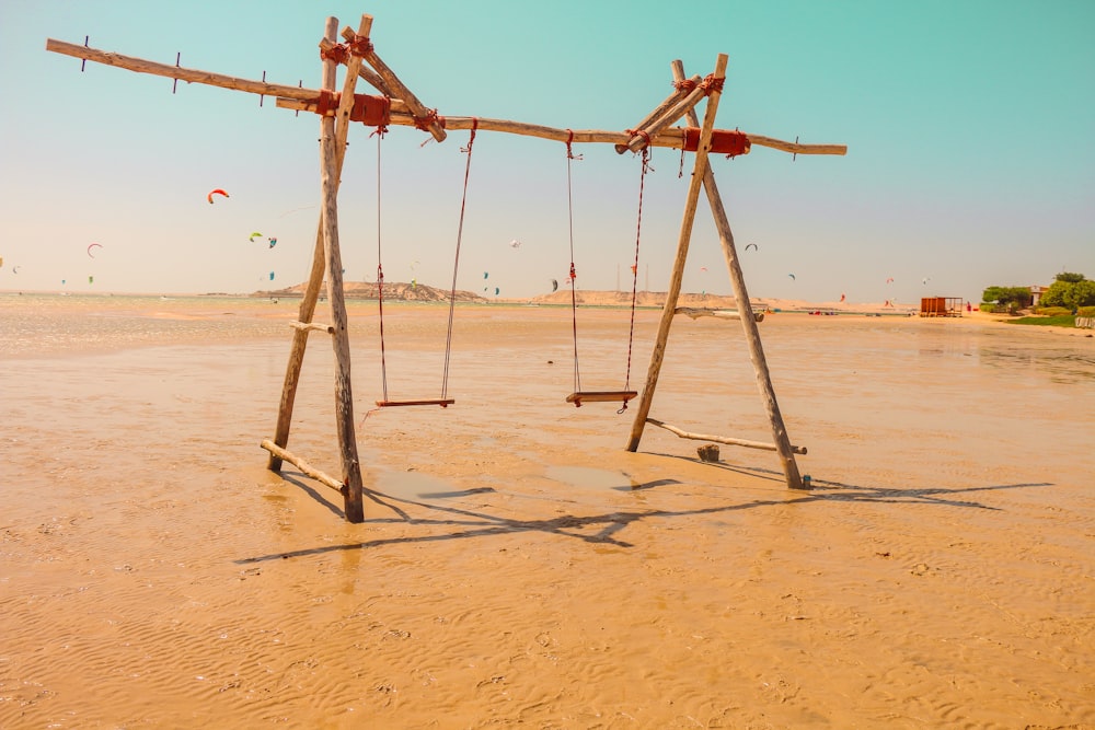 brown wooden swing on sand