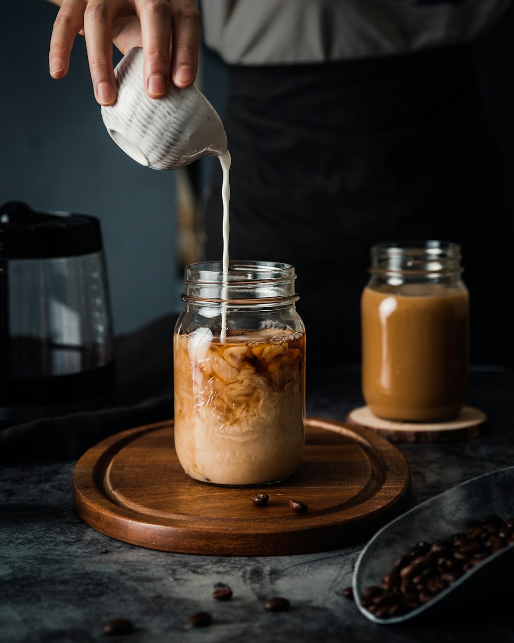 person pouring milk in clear glass container