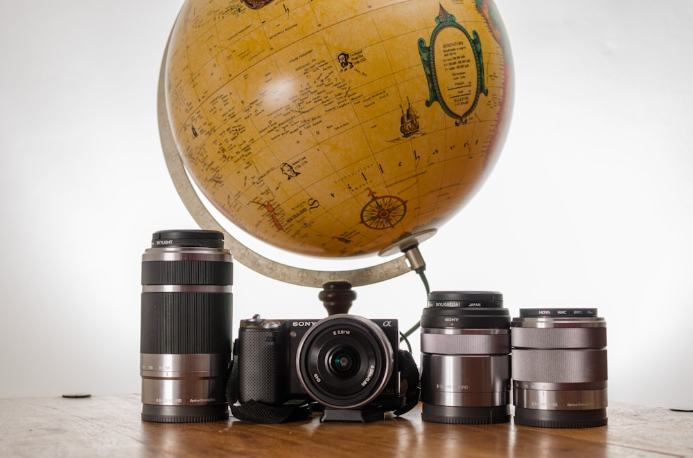 appareil photo reflex noir près du globe de bureau marron