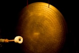 person striking large brass cymbal