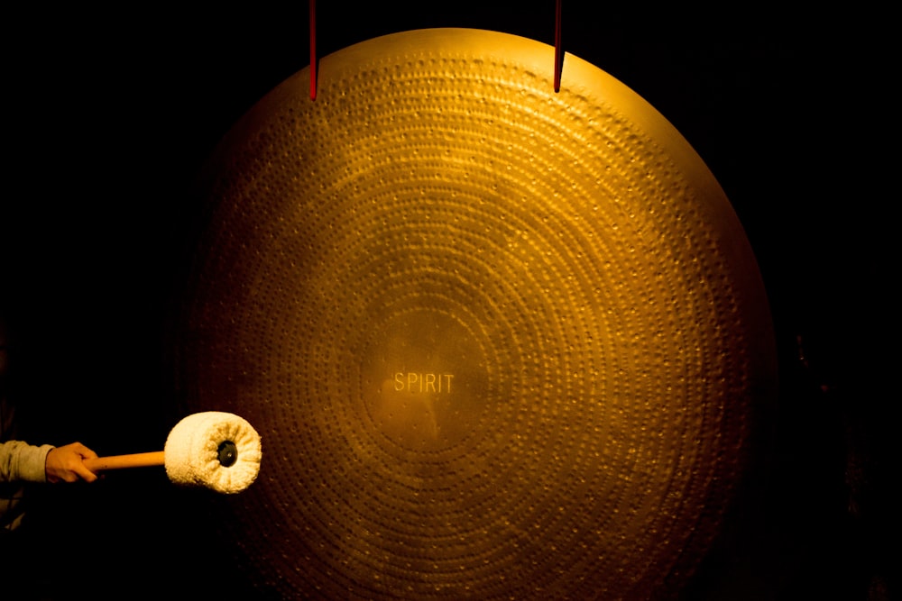 person striking large brass cymbal