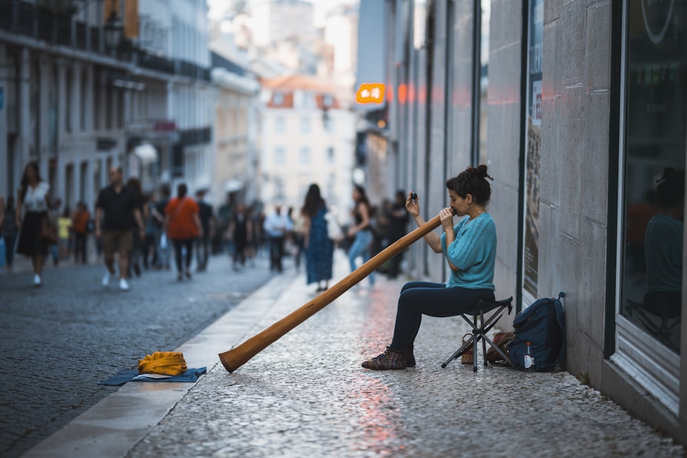 woman in teal elbow-sleeved shirt blowing big horn on street during daytime