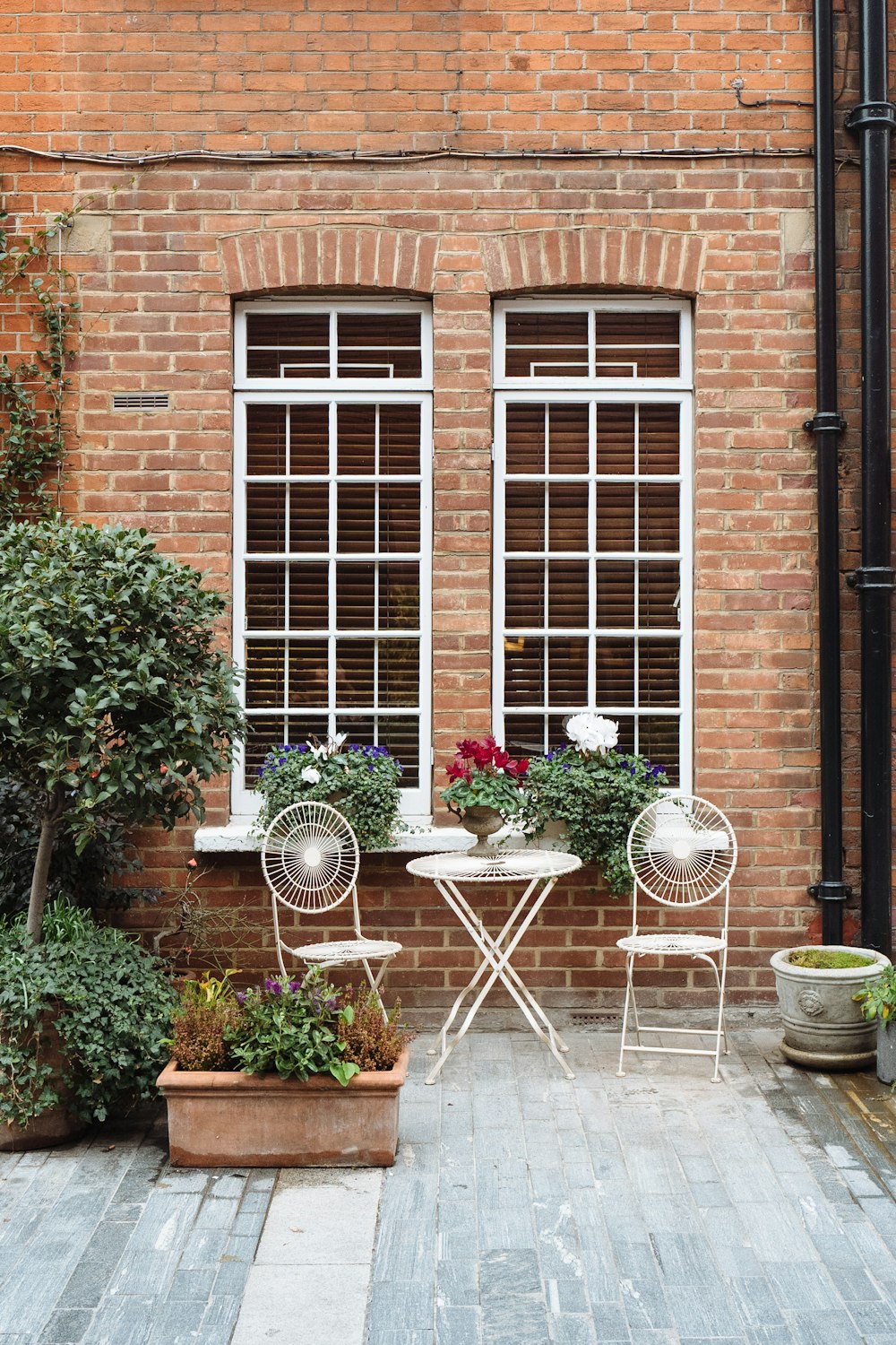 white metal bistro set outside house near white-framed windows