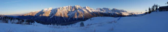 A panoramic view of snow-capped mountains and crystal-clear lake in Saint Moritz during golden hour.