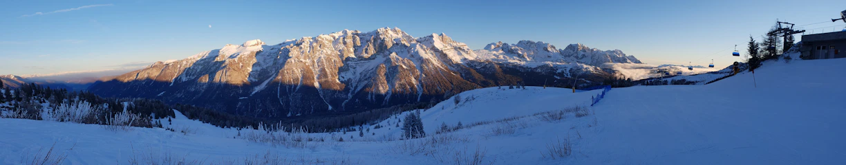 A panoramic view of snow-capped mountains and crystal-clear lake in Saint Moritz during golden hour.