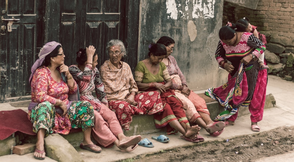 group of women sitting beside concrete building