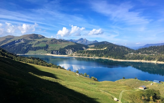 blue body of water surrounded by green mountain in Roselend Dam France