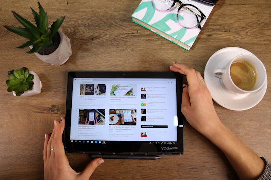 Close-up of a person reading a tech article on a tablet with notes and coffee nearby.