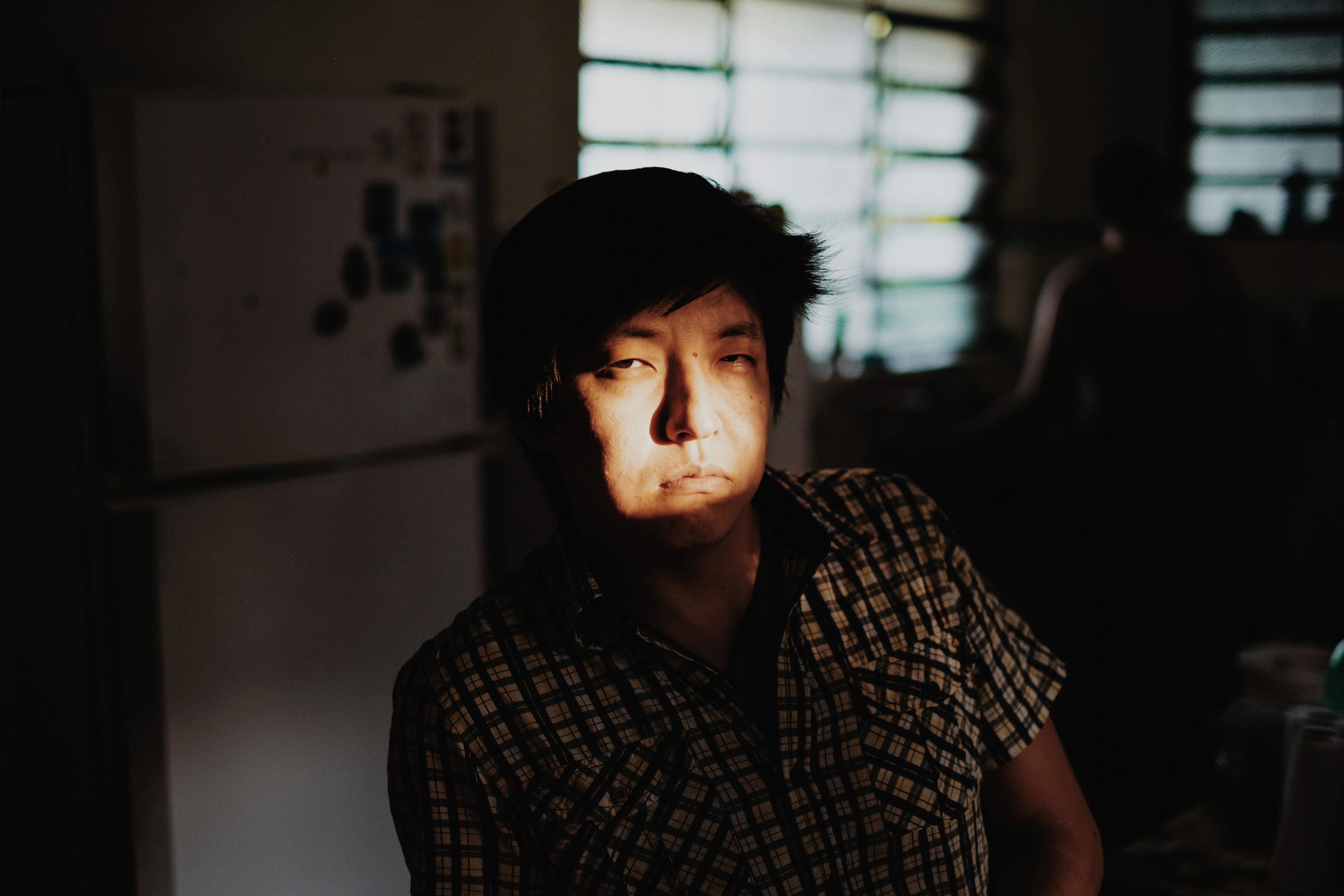 Hombre con camisa a cuadros cerca del refrigerador