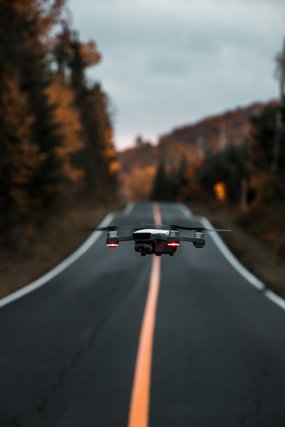 black and red drone in the middle of road near trees