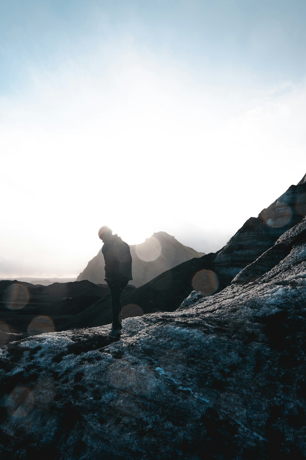 man in grey jacket standing on snowy mountain