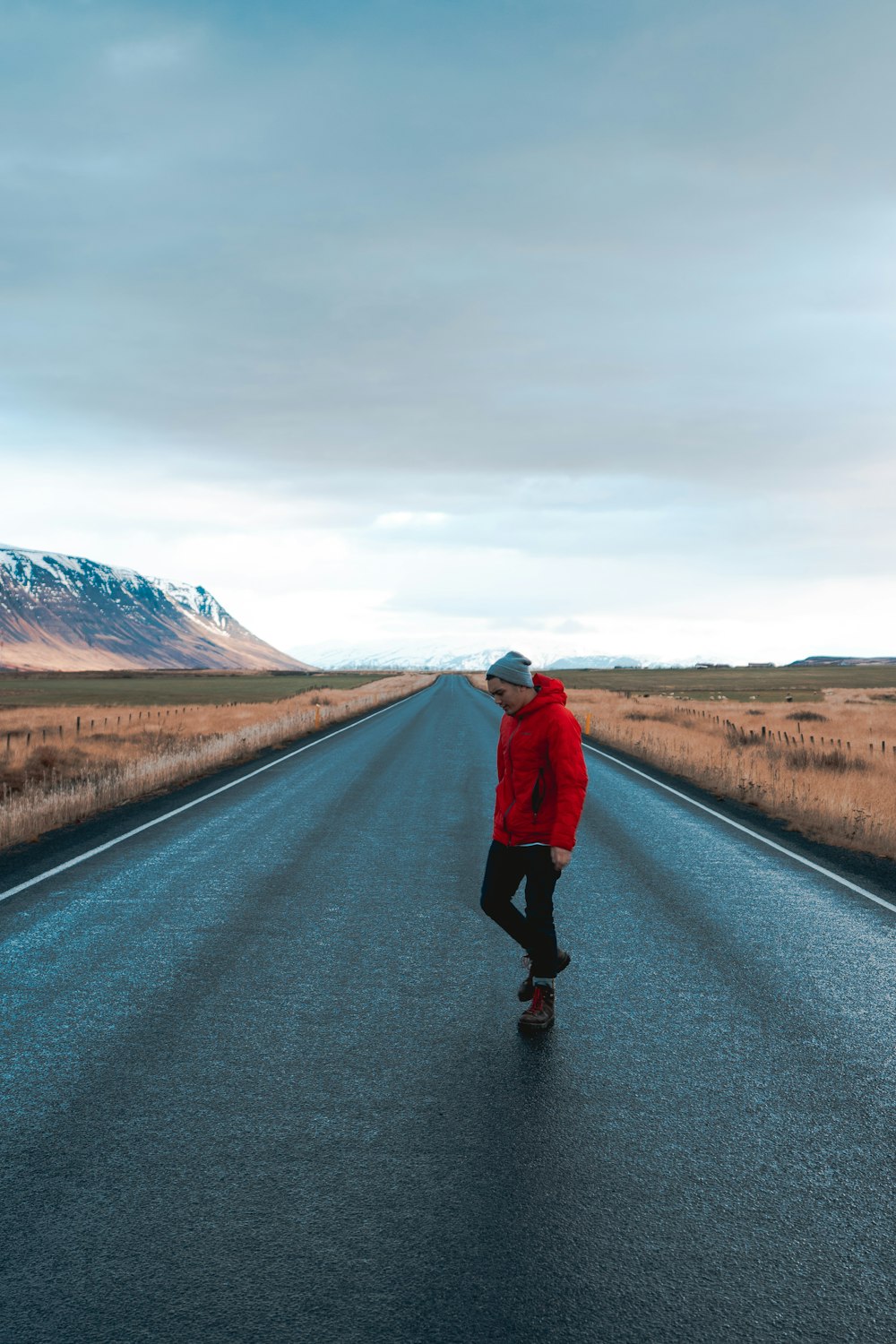 man in red hoodie standing on road