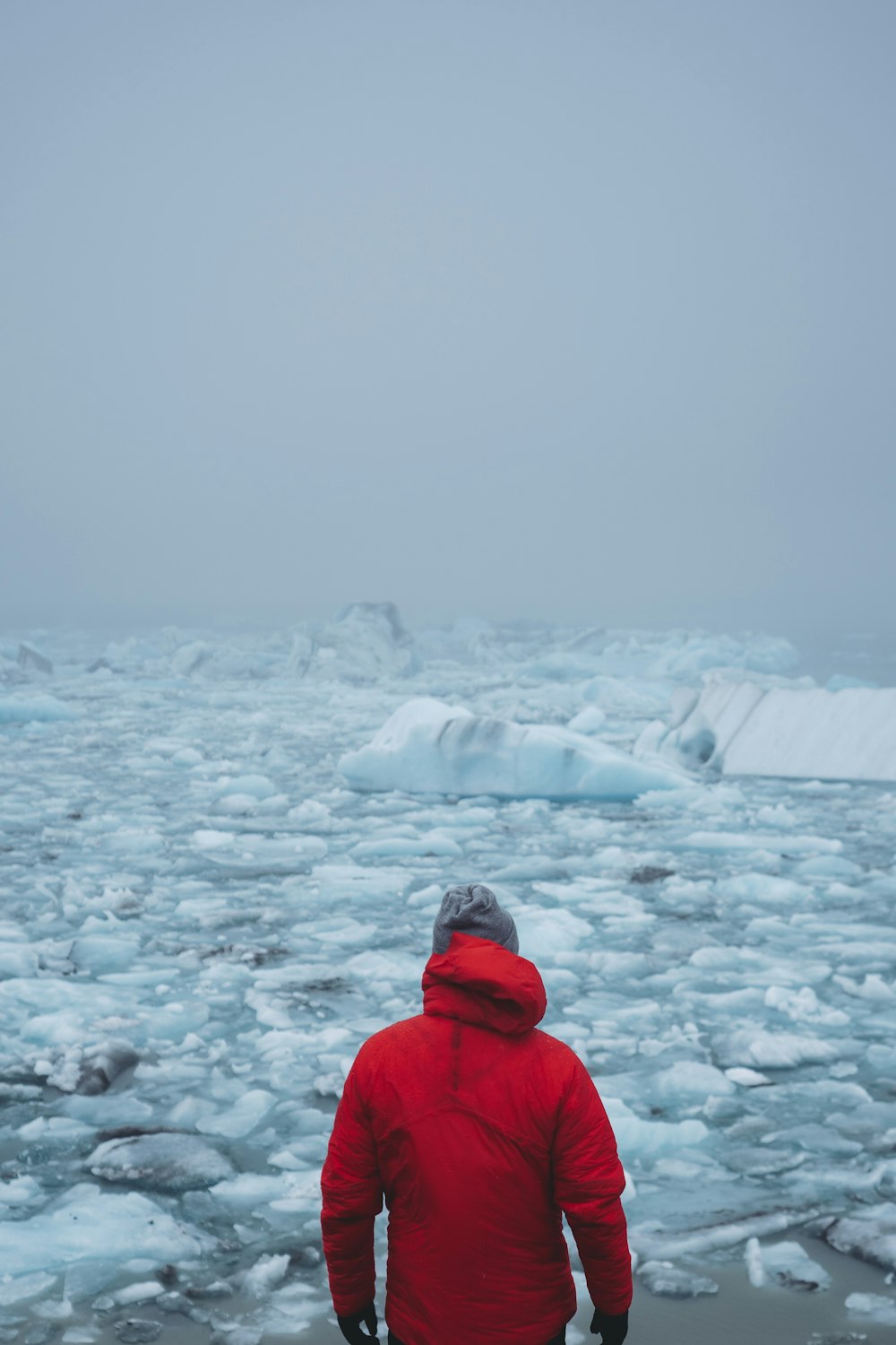 man in red coat standing in front of floating ice
