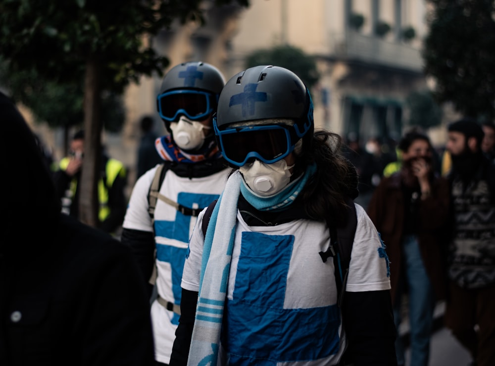 two persons wearing gas masks and helmets