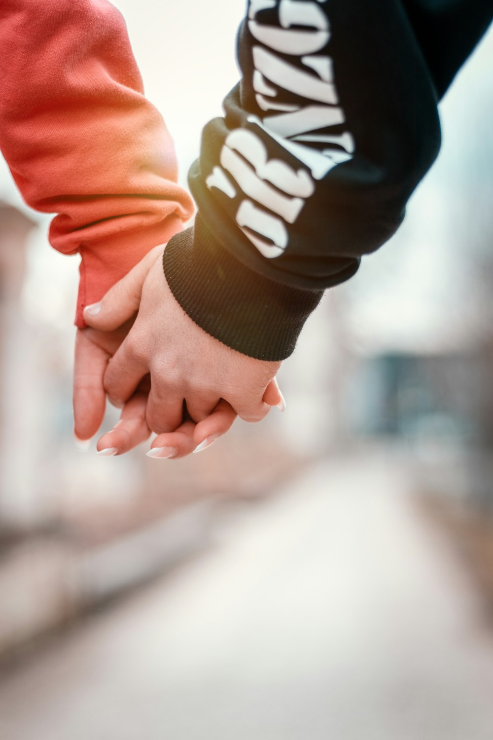 two person holding hands in selective focus photography