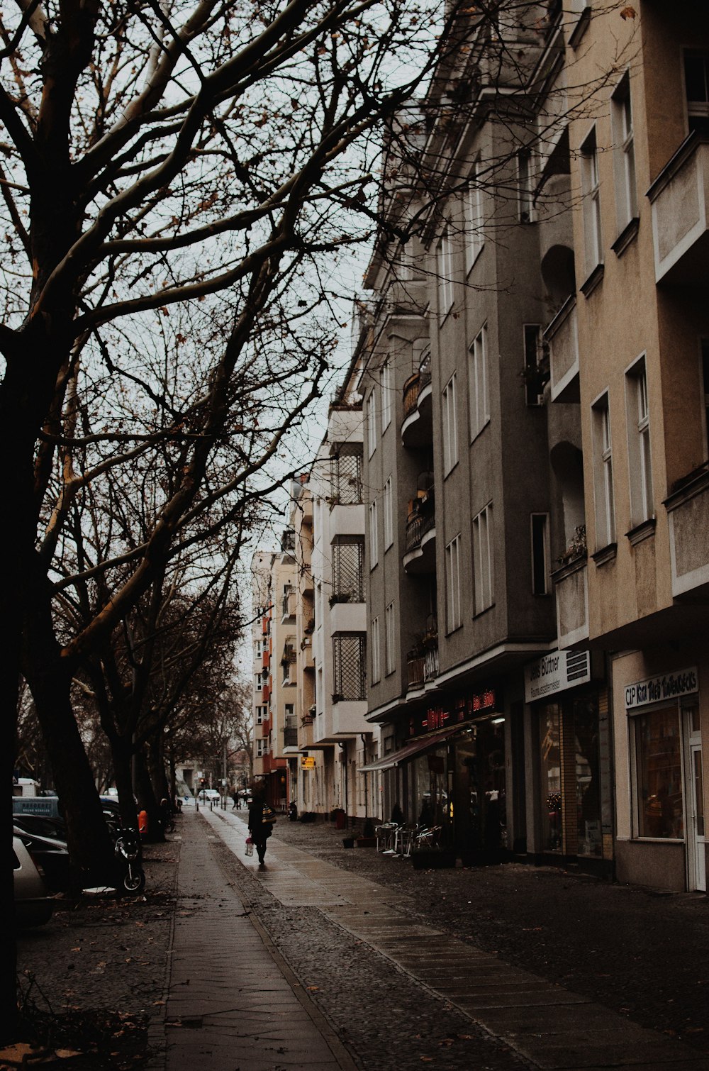 man running outside beige buildings fronting bear trees