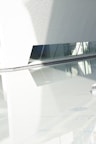 A sleek, minimalist still from a video shoot featuring smooth glass reflections and deep shadows.