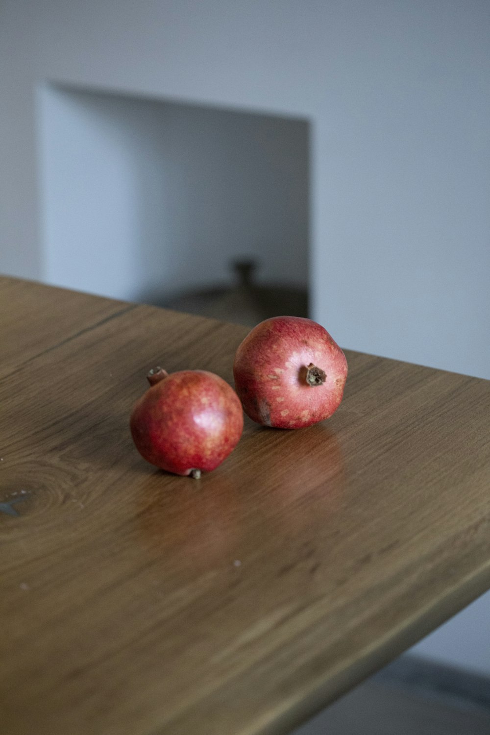 two small round red fruits on brown wooden table