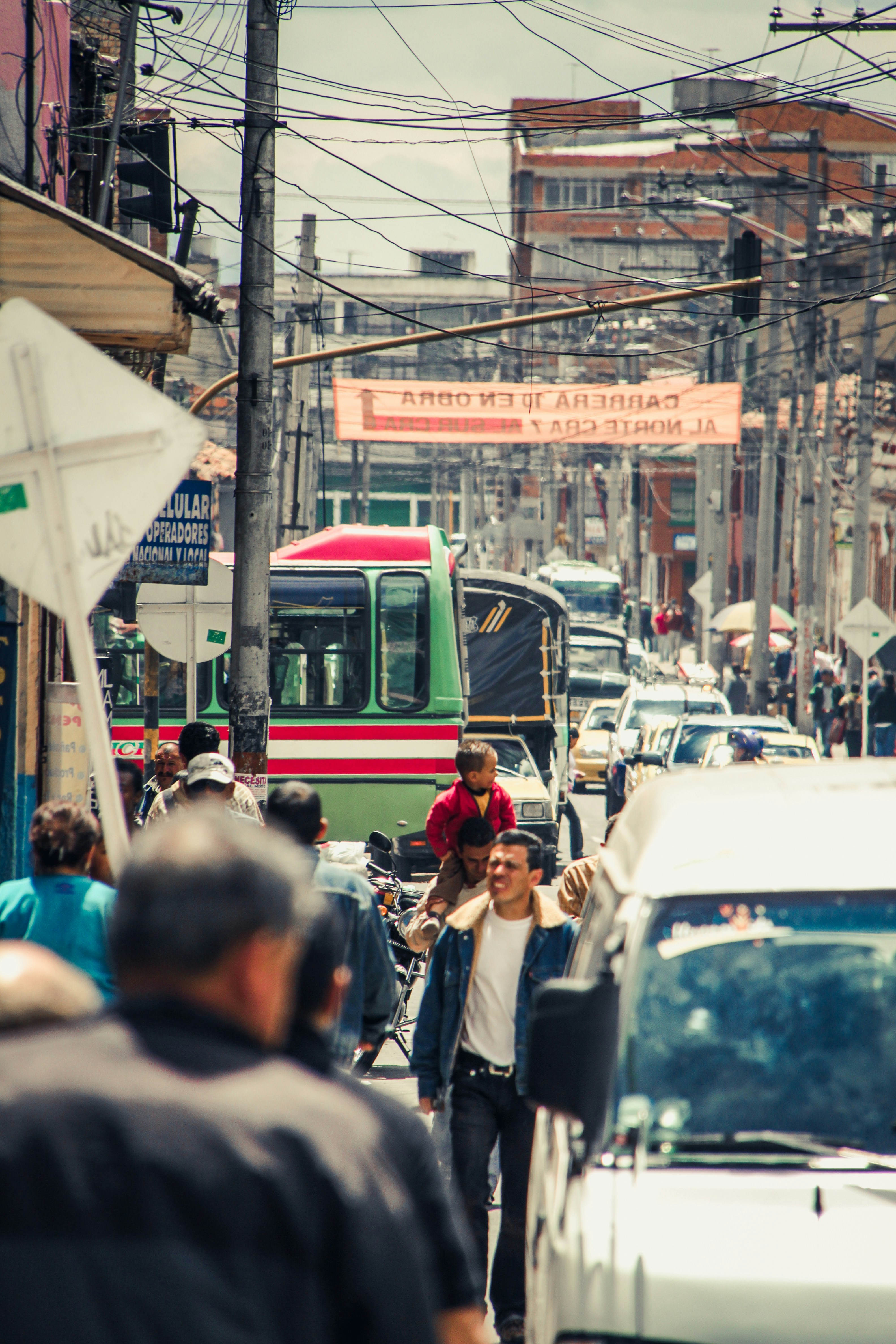 hombres caminando en una calle concurrida entre edificios y postes de servicios públicos durante el día