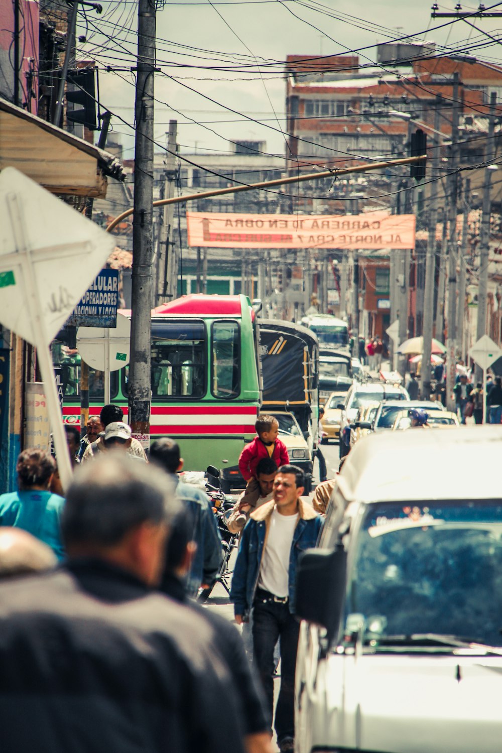 men walking on busy street between buildings and utility poles during day time