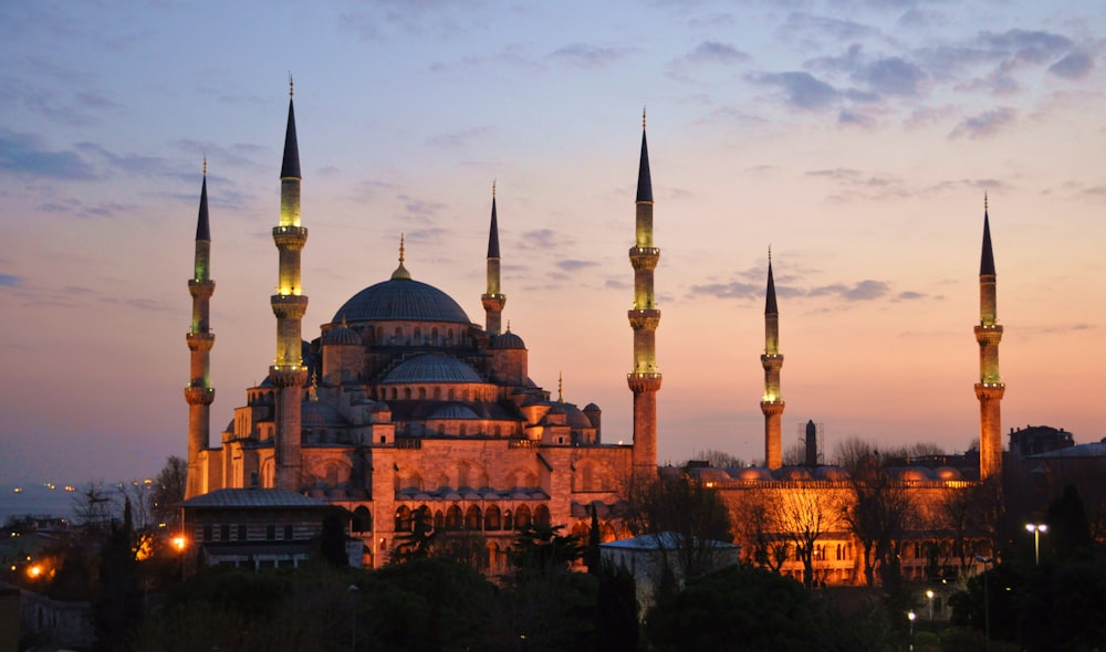 brown dome castle with towers lighted up during sunset