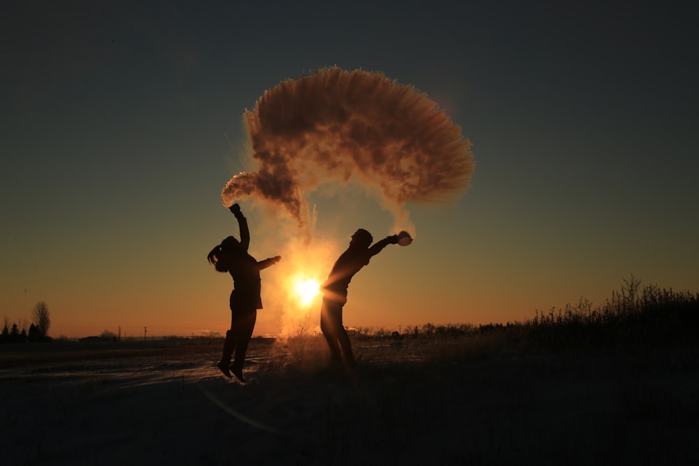 silhouette photography f man and woman throwing snow