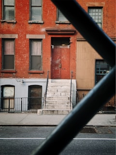 orange and white painted brick building seen through metal railings