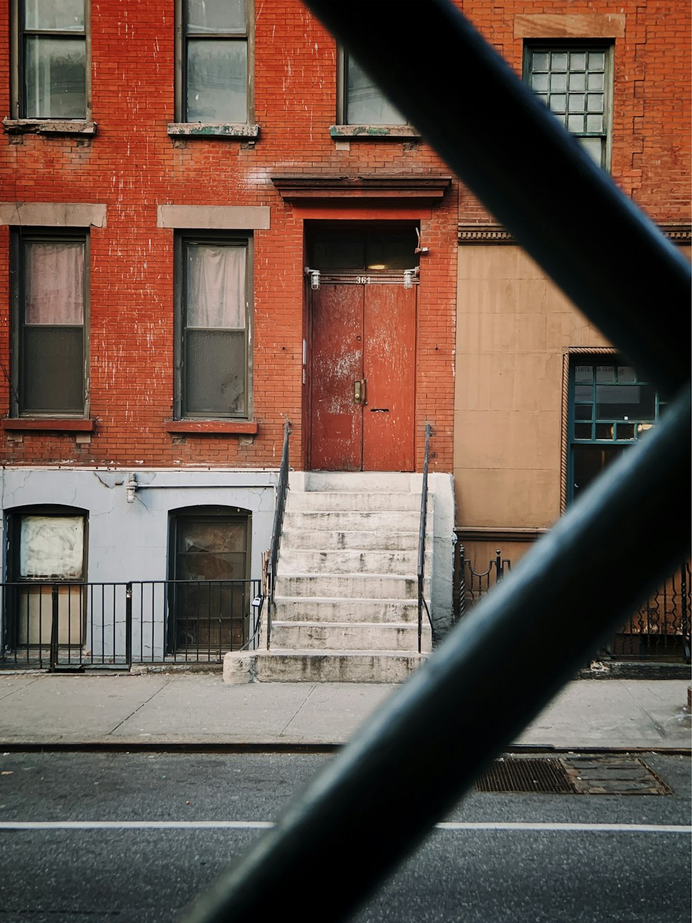 orange and white painted brick building seen through metal railings