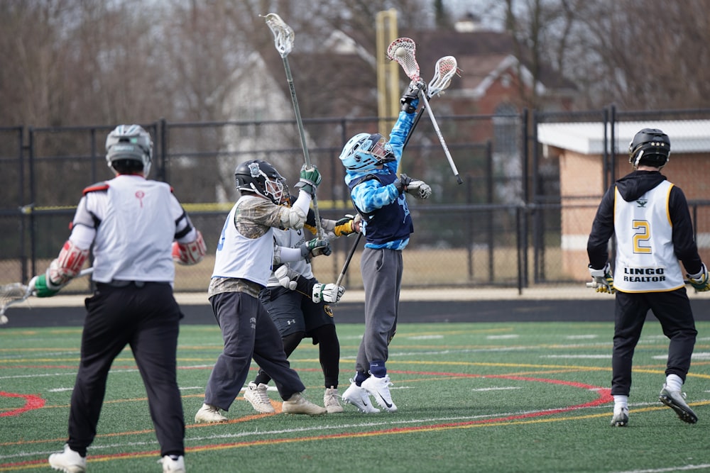 people playing lacrosse on green field during daytime