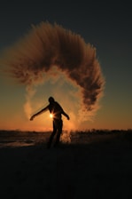 person standing and almost raising both hands on field during sunset