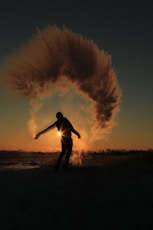 person standing and almost raising both hands on field during sunset