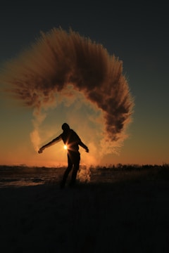 person standing and almost raising both hands on field during sunset