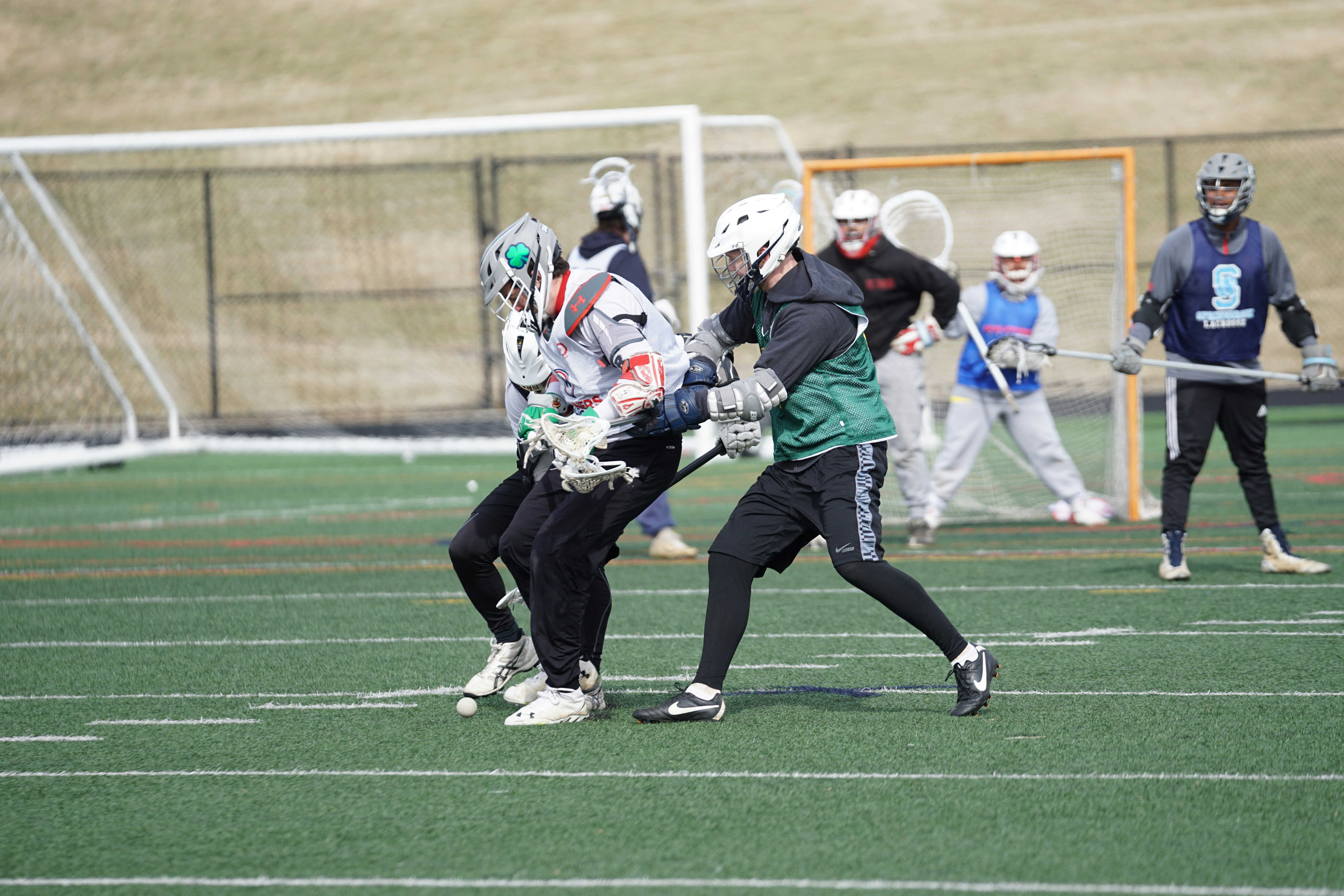 lacrosse players playing on field under white sky