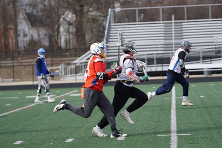 four men playing lacrosse game during daytime