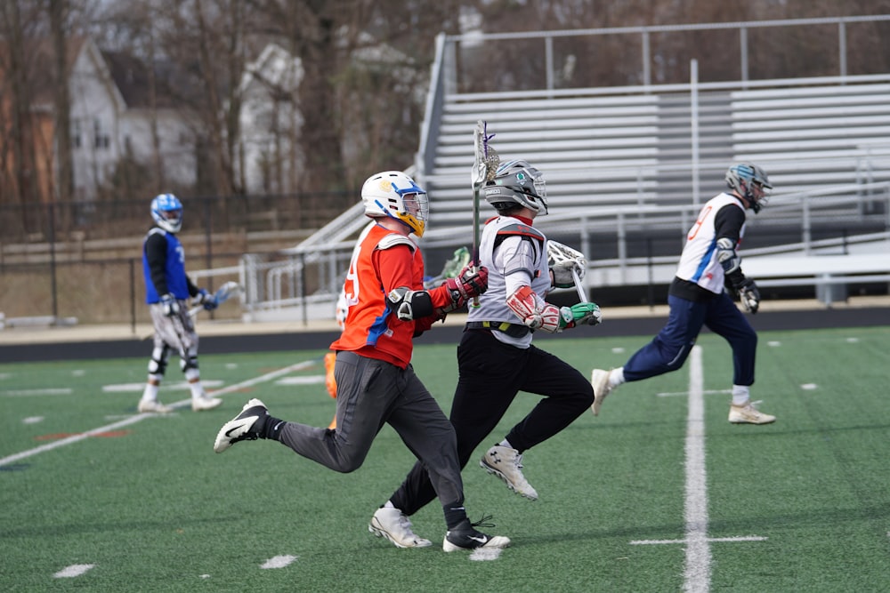 four men playing lacrosse game during daytime