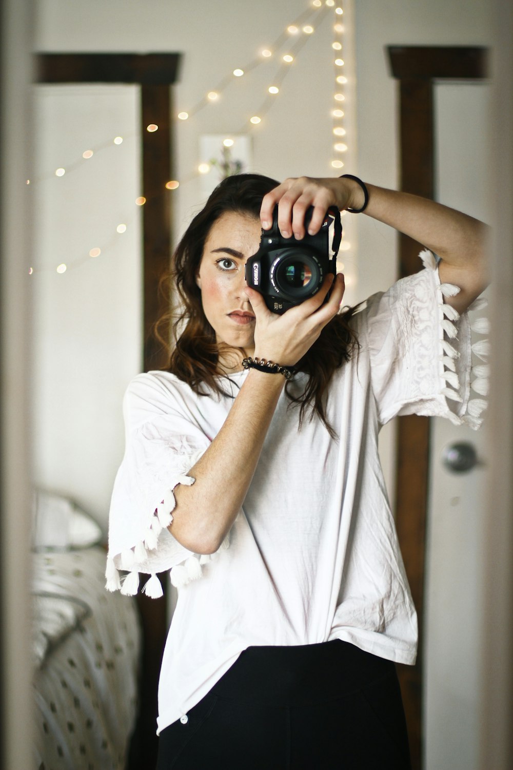 Mujer en top blanco mirando a través de la mirilla de la cámara