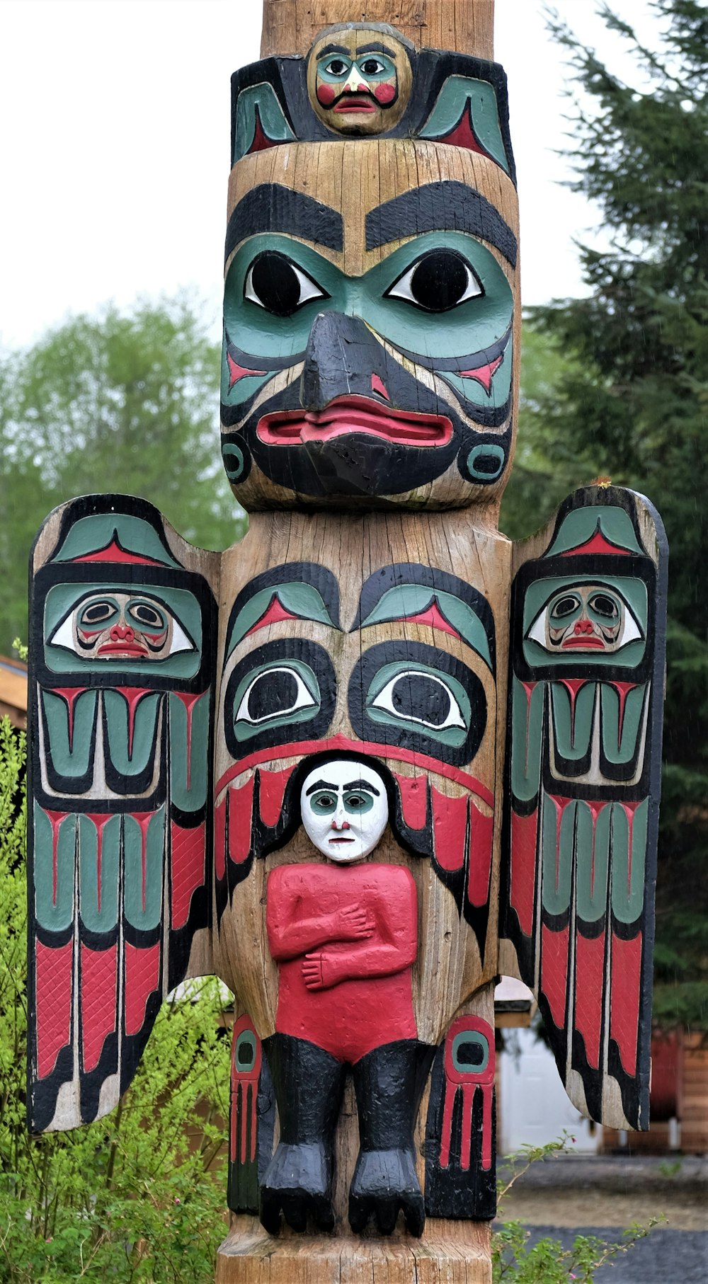 brown, red, and black totem pole near trees