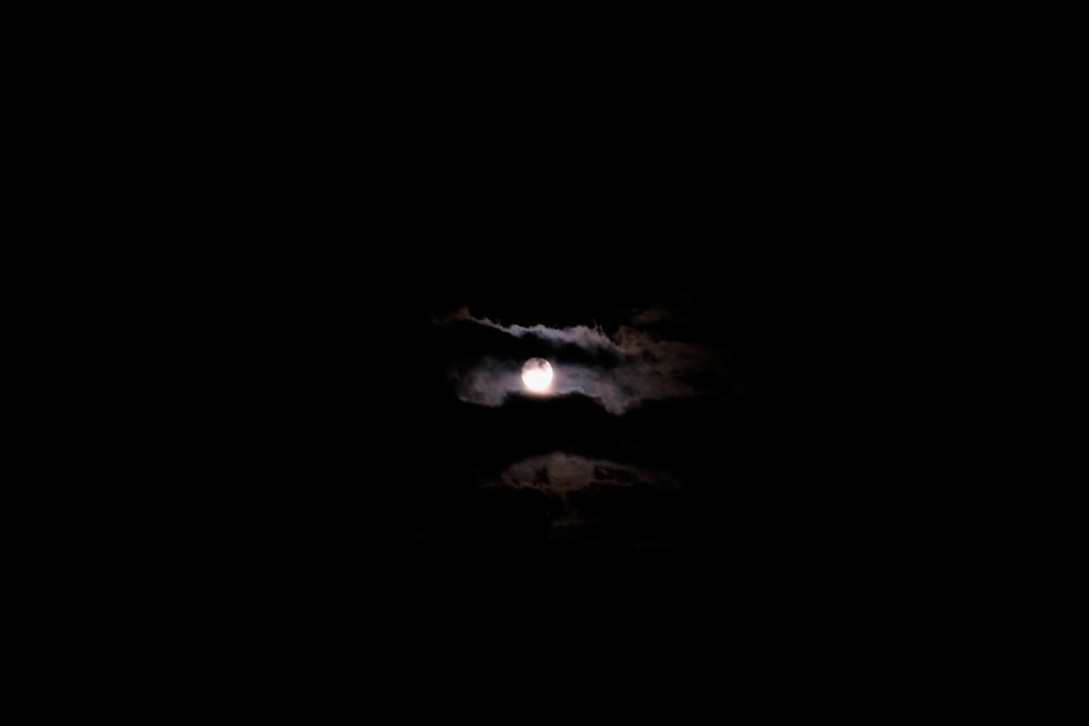 full moon covered by clouds at night time